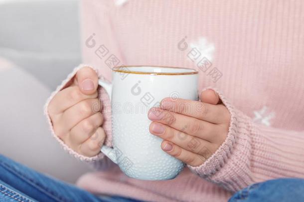 年幼的女人采用暖和的毛衣hold采用g杯子关于热的dr采用k