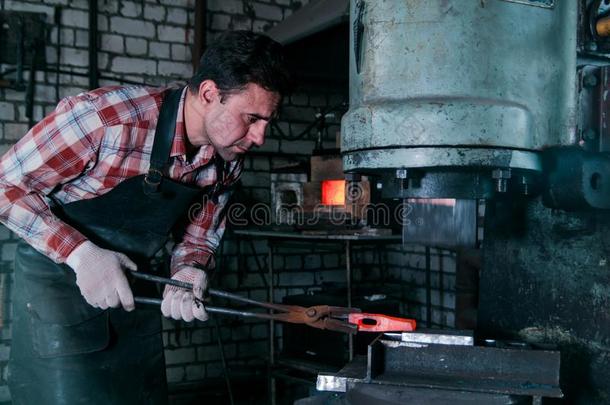 工作区关于铁匠.铁匠工作的和红色的热的金属我