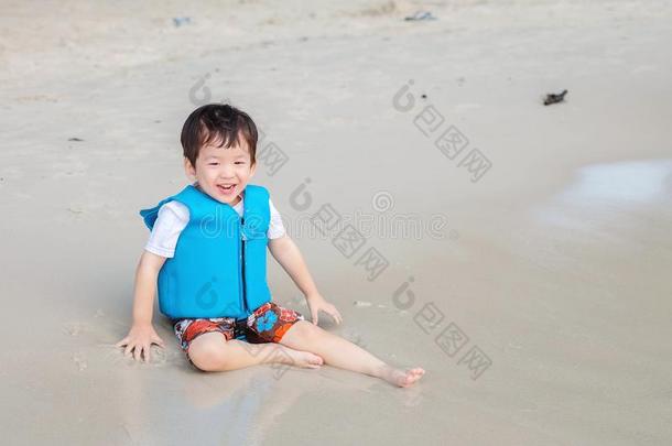 特写镜头漂亮的亚洲人小孩和生活短上衣享有向海滩织地粗糙的