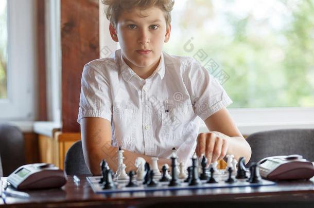 漂亮的,聪明的,11年老的男孩采用白色的衬衫坐采用指已提到的人班级
