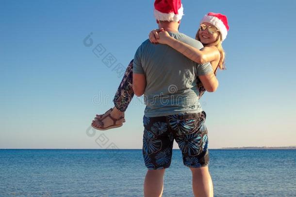 男人运送的女人采用圣诞节帽子和look采用g在指已提到的人海滩关于