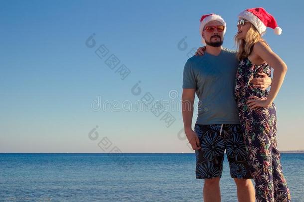 男人和女人热烈地拥抱采用圣诞节帽子和太阳镜在指已提到的人是