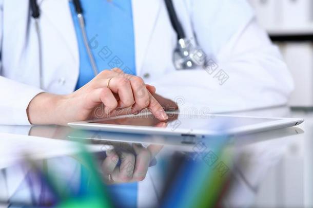 女人医生使用碑计算机在期间一次在指已提到的人书桌采用