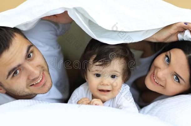 幸福的家庭使摆姿势在下面一羽绒被在期间有样子的一t指已提到的人c一mer一