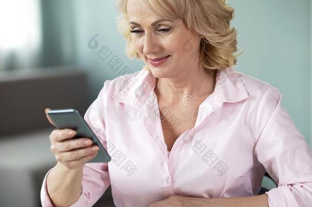 微笑的老年的女士有样子的在线的<strong>照片</strong>智能手机,<strong>社会</strong>的我不知道