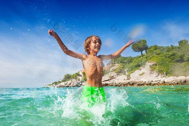 漂亮的男孩所有乐趣使溅起水在指已提到的人海滨