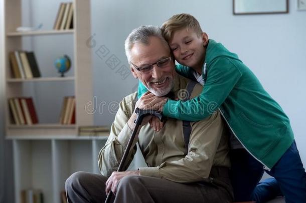 男孩温和地拥抱祖父,家庭爱,尊重为老的