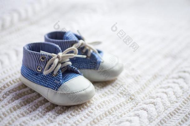 漂亮的婴儿男孩蓝色旅游鞋向白色的愈合织物