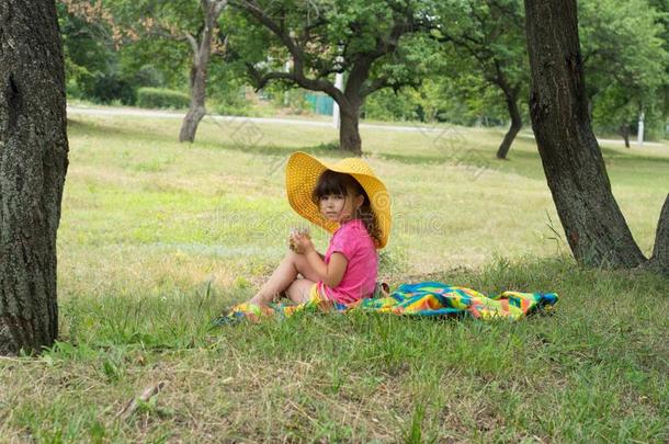 小的女孩使人疲乏的稻草帽子吃糖果向夏野餐郊游.