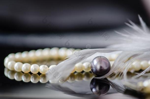 白色的珍珠项链,黑的珍珠,和灰色的羽毛