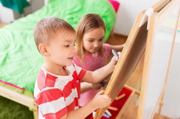 幸福的小孩绘画向画架或轻弹板在家