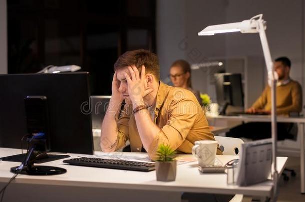 强调男人在计算机显示屏在夜办公室