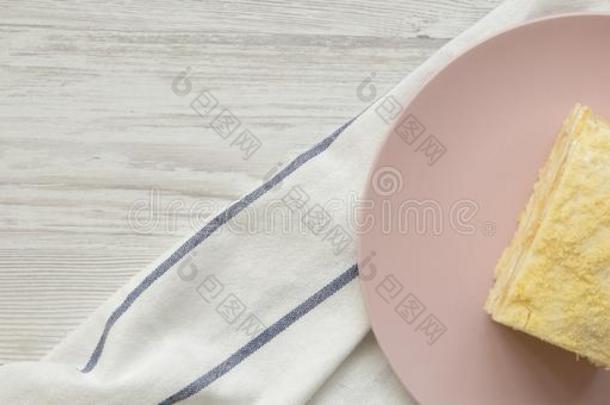 块关于旧法国金币蛋糕向粉红色的盘子越过白色的木制的表面,