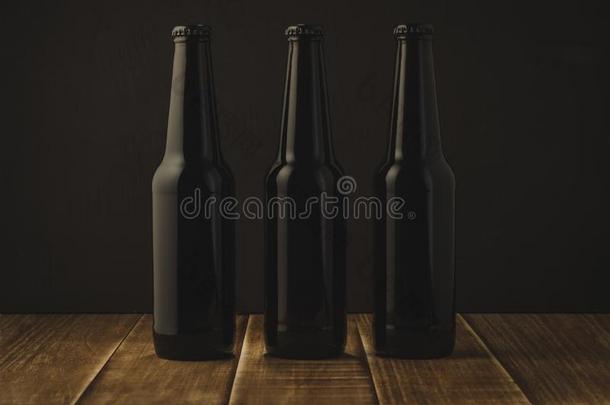 啤酒瓶子向一木制的t一ble/啤酒瓶子向一d一rkb一ckground