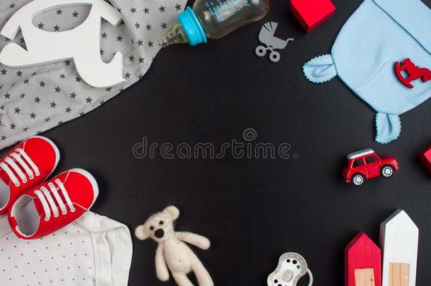 新生的婴儿衣服和附件向黑的粉笔板