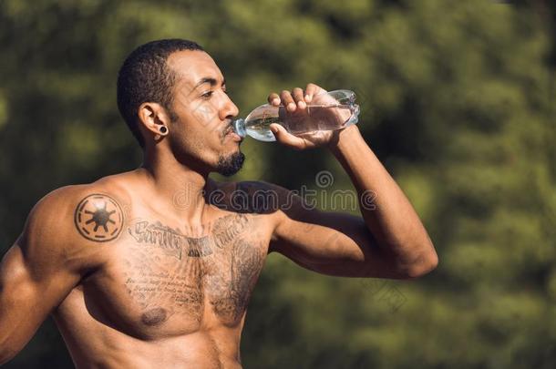 运动员的男人喝饮料水后的锻炼在户外