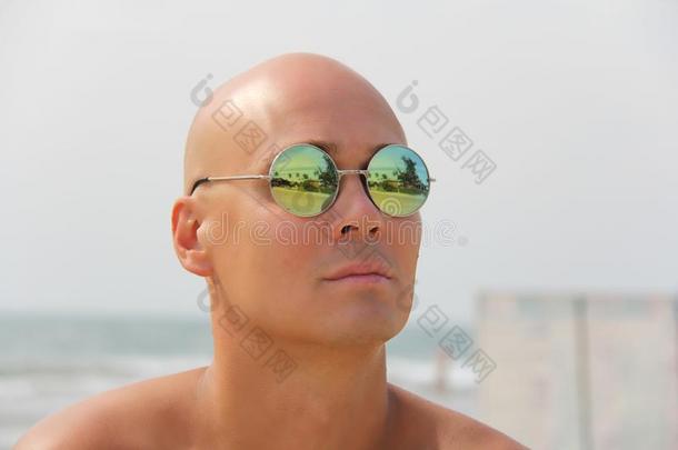 秃头的男人采用镜子太阳镜.一美丽的鞣酸处理的男人向真空