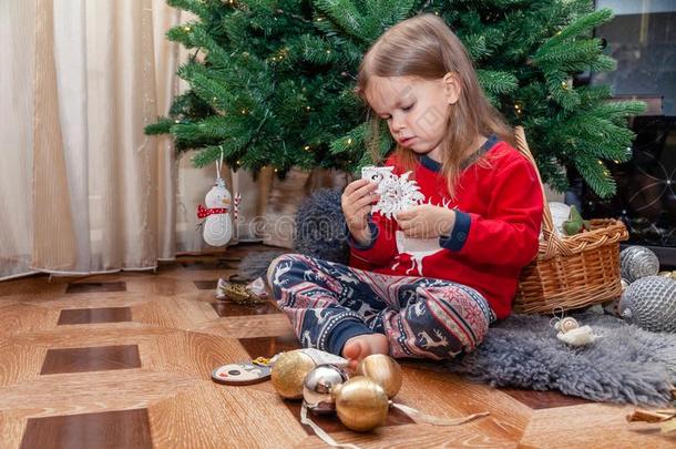 美丽的亚麻色的女孩采用节日的衣服分类圣诞节树玩具