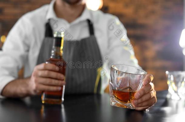 酒吧间销售酒精饮料的人和玻璃和瓶子关于威士忌酒在柜台采用条