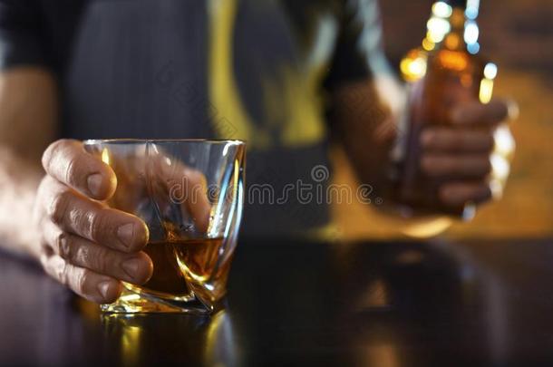 酒吧间销售酒精饮料的人和玻璃和瓶子关于威士忌酒在柜台采用条
