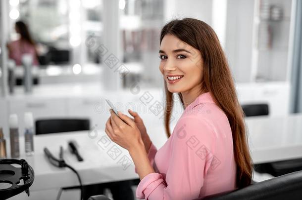 微笑的女人是（be的三单形式一次在近处镜子采用美好沙龙