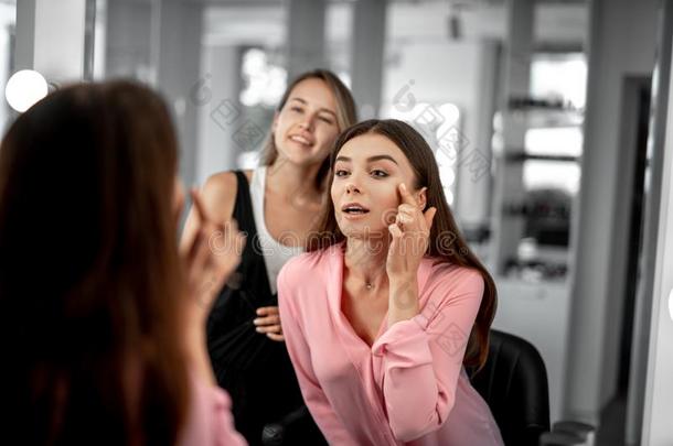 年幼的女人是（be的三单形式仔细检查化妆采用镜子和她styl是（be的三单形式t