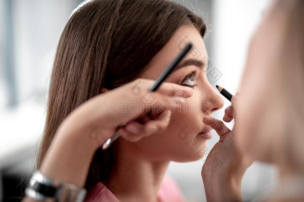 化妆艺术家是（be的三单形式强调下方的眼睑和黑的眼线膏