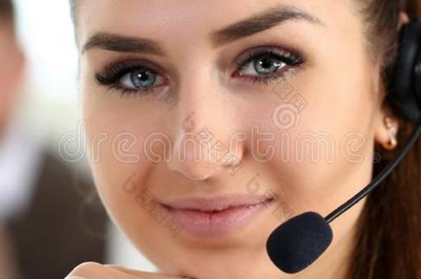 美丽的黑头发的妇女微笑的呼唤中心店员在使工作