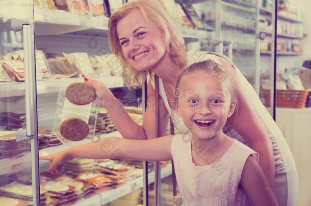 母亲和女儿购买已冷的foodstuff粮食采用超级市场