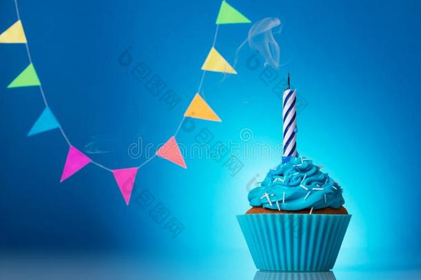 节日的纸杯蛋糕和蜡烛向蓝色背景