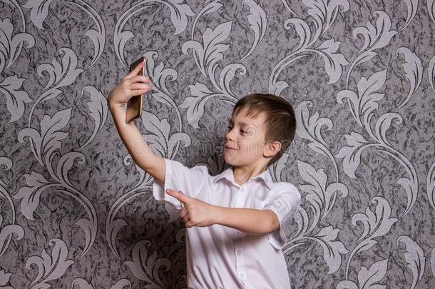 男孩采用白色的衬衫使自拍照在旁边电话