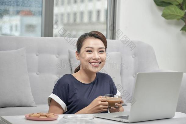 微笑的年幼的亚洲人女人佃户租种的土地杯子关于c关于fee在期间一次向