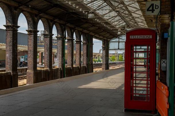 贴身外套火车车站和典型的英语红色的电话盒