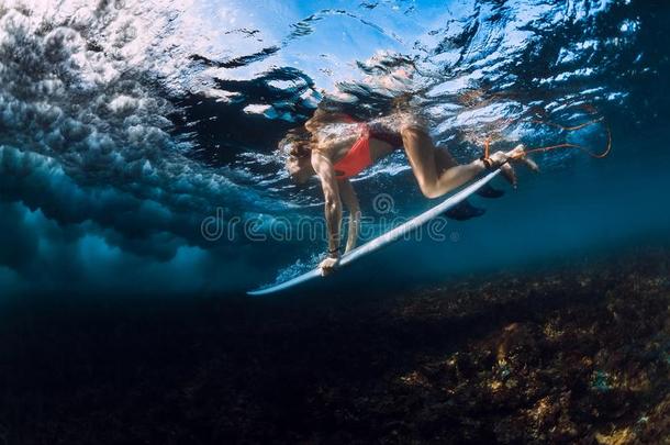 冲浪运动员女人潜水在水中的和冲浪板,在下面波浪