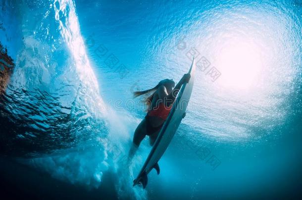 有魅力的冲浪运动员女人潜水在水中的和在下面桶波浪