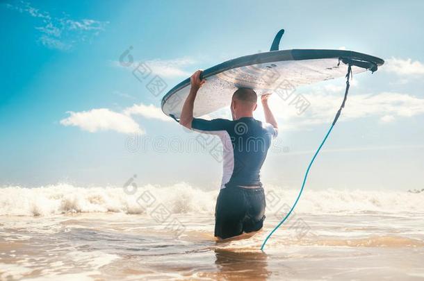 年幼的男人冲浪运动员和长的板向上端进行向指已提到的人海向aux.用以构成完成式及完成式的不定式