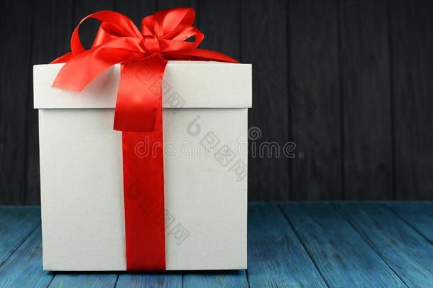 白色的赠品盒和一大的红色的弓向一蓝色木制的b一ckground