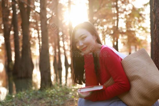 年幼的亚洲人中国人女人阅读采用指已提到的人秋水红色的森林