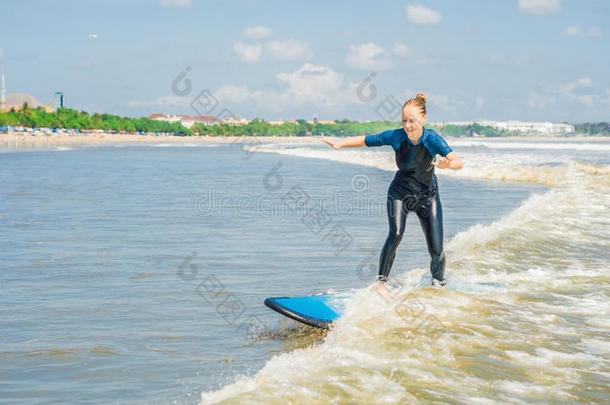 快乐的年幼的女人新手冲浪运动员和蓝色海浪有乐趣向subjectmatterarea主题区