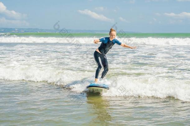 快乐的年幼的女人新手冲浪运动员和蓝色海浪有乐趣向subjectmatterarea主题区