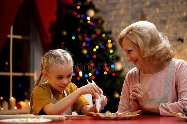 兴奋的女孩装饰圣诞节甜饼干和奶奶,家庭节日的
