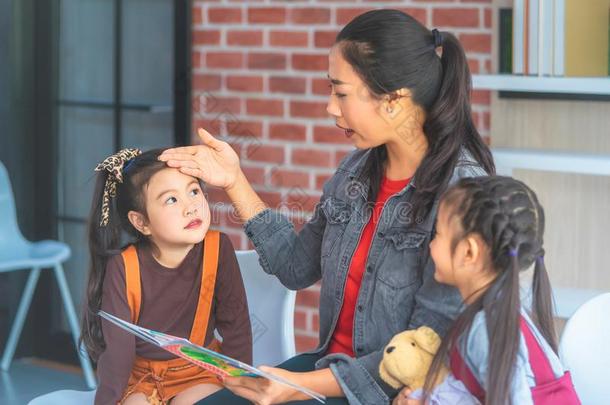 教师阅读故事书向幼儿园学生手向上端