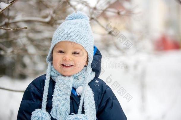 漂亮的小的蹒跚行走的人男孩,演奏在户外和雪向一冬