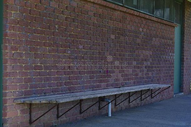 空的学校长凳和砖墙向背景