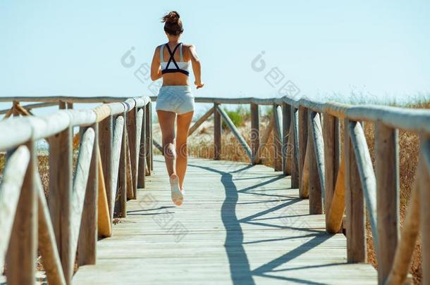 积极的有关运动的女人采用运动衣服向洋海岸jogg采用g