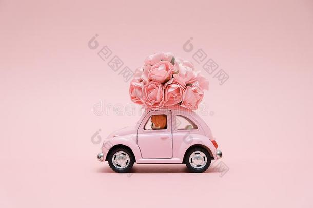 粉红色的制动火箭玩具汽车递送花束向粉红色的背景.二月