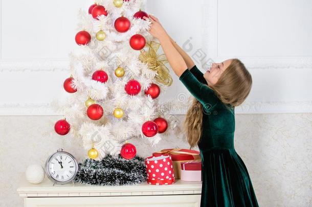 小孩悬挂圣诞节装饰球向人造的树.小孩aux.能够