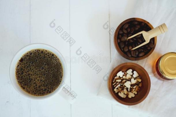 新鲜的泡热的黑的咖啡豆采用纯的白色的陶器的杯子向白色的