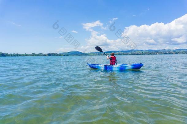 年幼的男孩涉水蓝色和白色的爱斯基摩单人划子采用海港