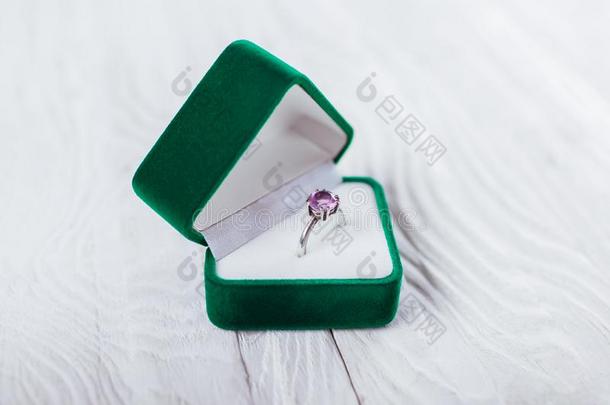 银戒指和紫蓝色宝石采用绿色的赠品盒向白色的背景.